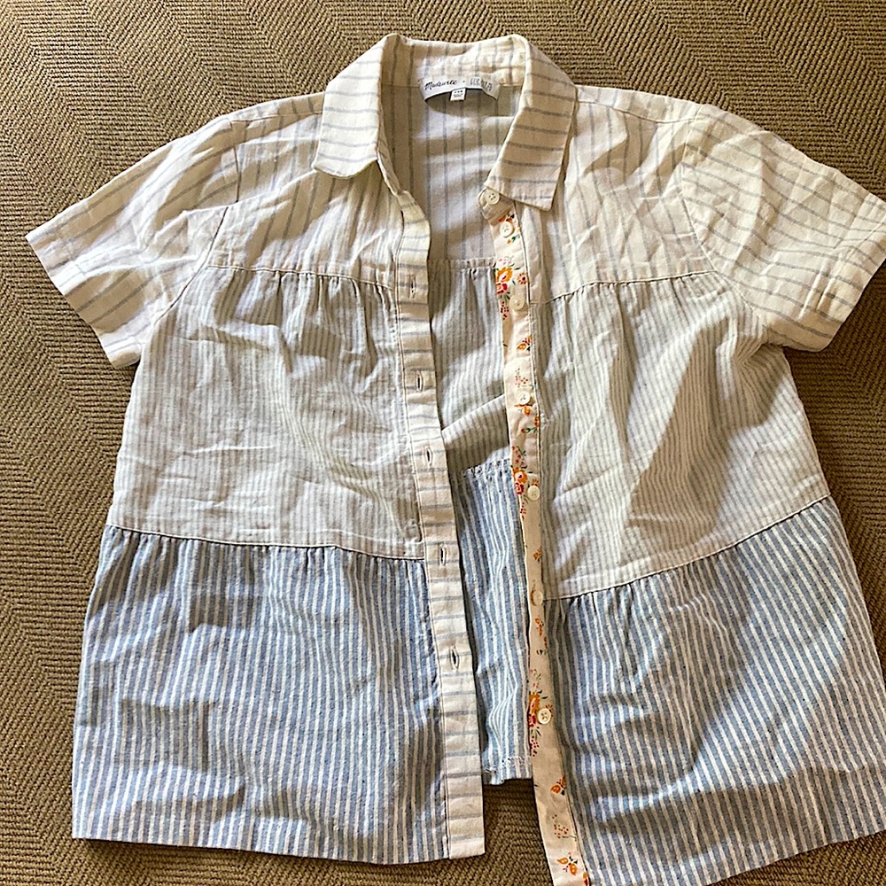 It has white and blue stripes with a floral pattern on the button line